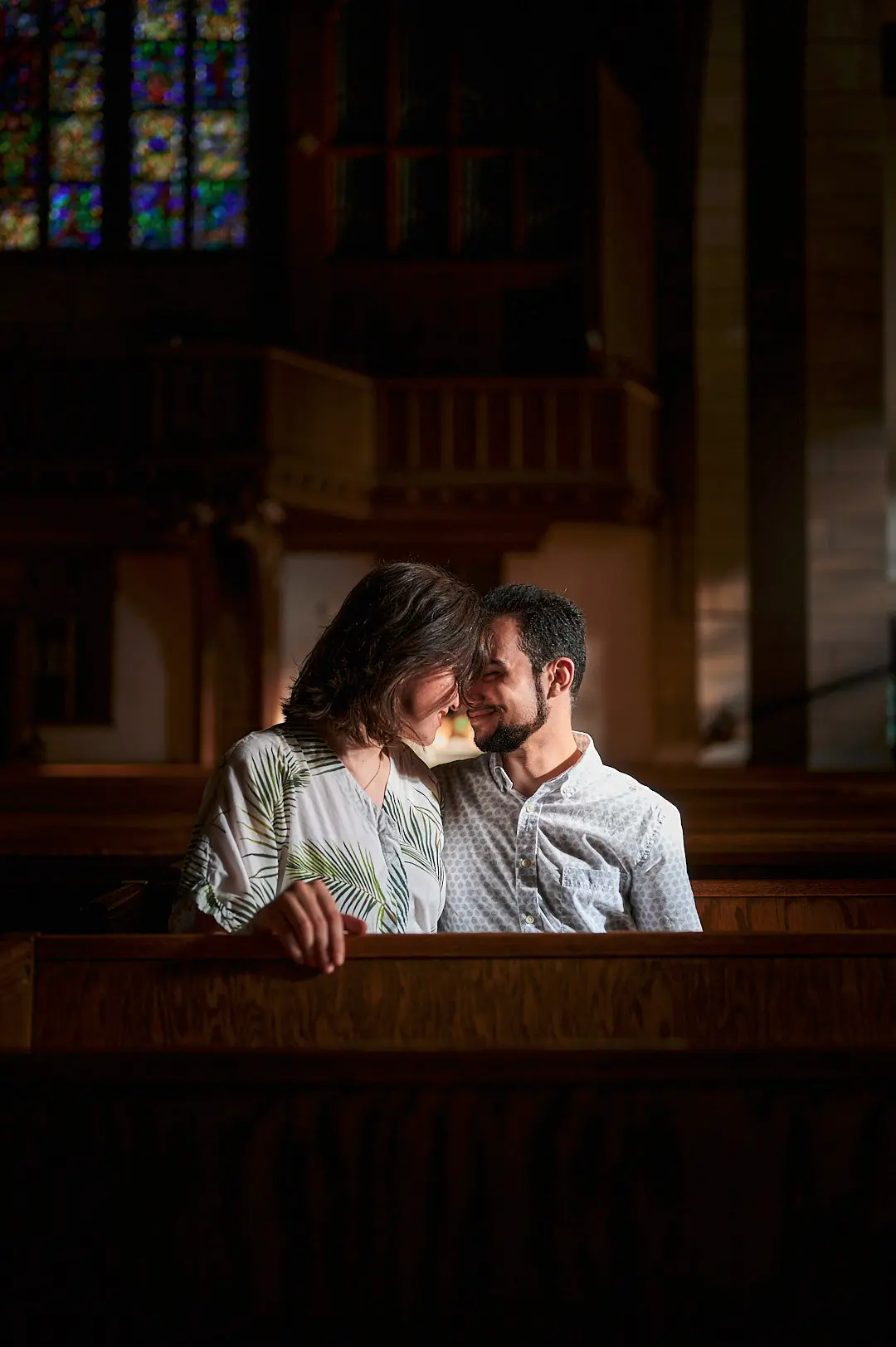 a man and woman sit in a church, gazing into each other's eyes